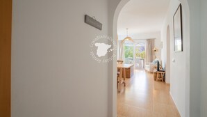 Un pasillo que conduce a un comedor con una mesa y sillas, una lámpara colgante y un cartel en la pared.