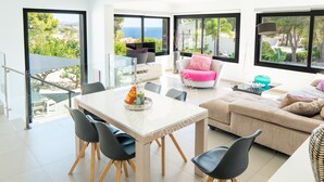 A modern living room with a dining area, large windows, and a view of the outdoors. - CostaBlancaDreams - Mila in Benissa (Calpe)