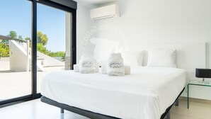 A modern bedroom with a large bed, a glass side table, and an air conditioning unit. - CostaBlancaDreams - Mila in Benissa (Calpe)