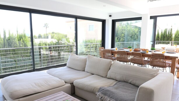 Un salon moderne avec un grand canapé, une table basse en bois et un coin repas comprenant une table et des chaises.