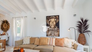 Una sala de estar con un sofá color beige, una mesa de centro con velas y una obra de arte grande enmarcada en la pared.