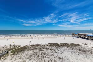 A beach with a wooden pier and beach umbrellas.