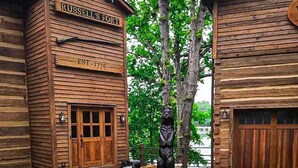 A rustic log cabin with a sign reading 'Russell's Fort EST. 1775' and a statue of a bear.