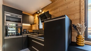Eine moderne Küche mit schwarzen Schränken, Edelstahlgeräten und einem eingebauten Backofen.