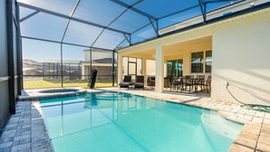 Una piscina con cerramiento de vidrio, mobiliario exterior y vistas del entorno.