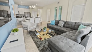 Ein modernes Wohnzimmer mit einem grauen Sofa, einem Couchtisch und einer TV-Kommode.