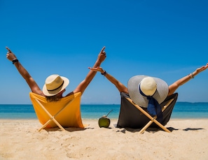 Two people sitting on beach chairs facing the sea, with their arms raised. - The Lighthouse Retreat, Little Corn island, Nicaragua (Corn Islands)