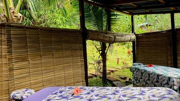 A room with a bed, a table, and a view of a garden.