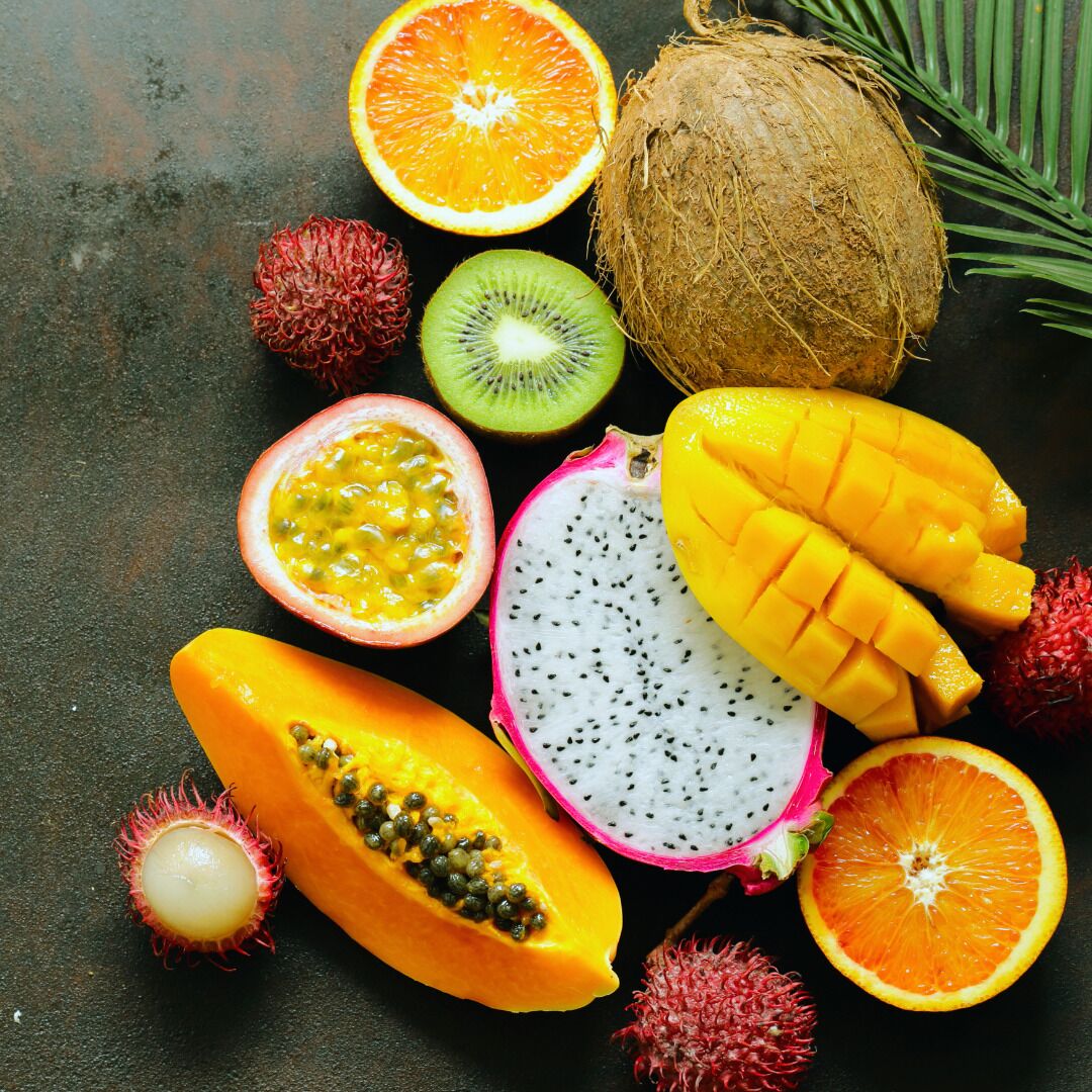 A variety of tropical fruits including mango, papaya, dragon fruit, kiwi, rambutan, and orange.