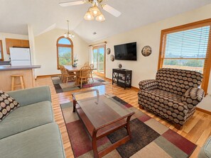 A living room with a sofa, a coffee table, and a dining area with chairs and a table.