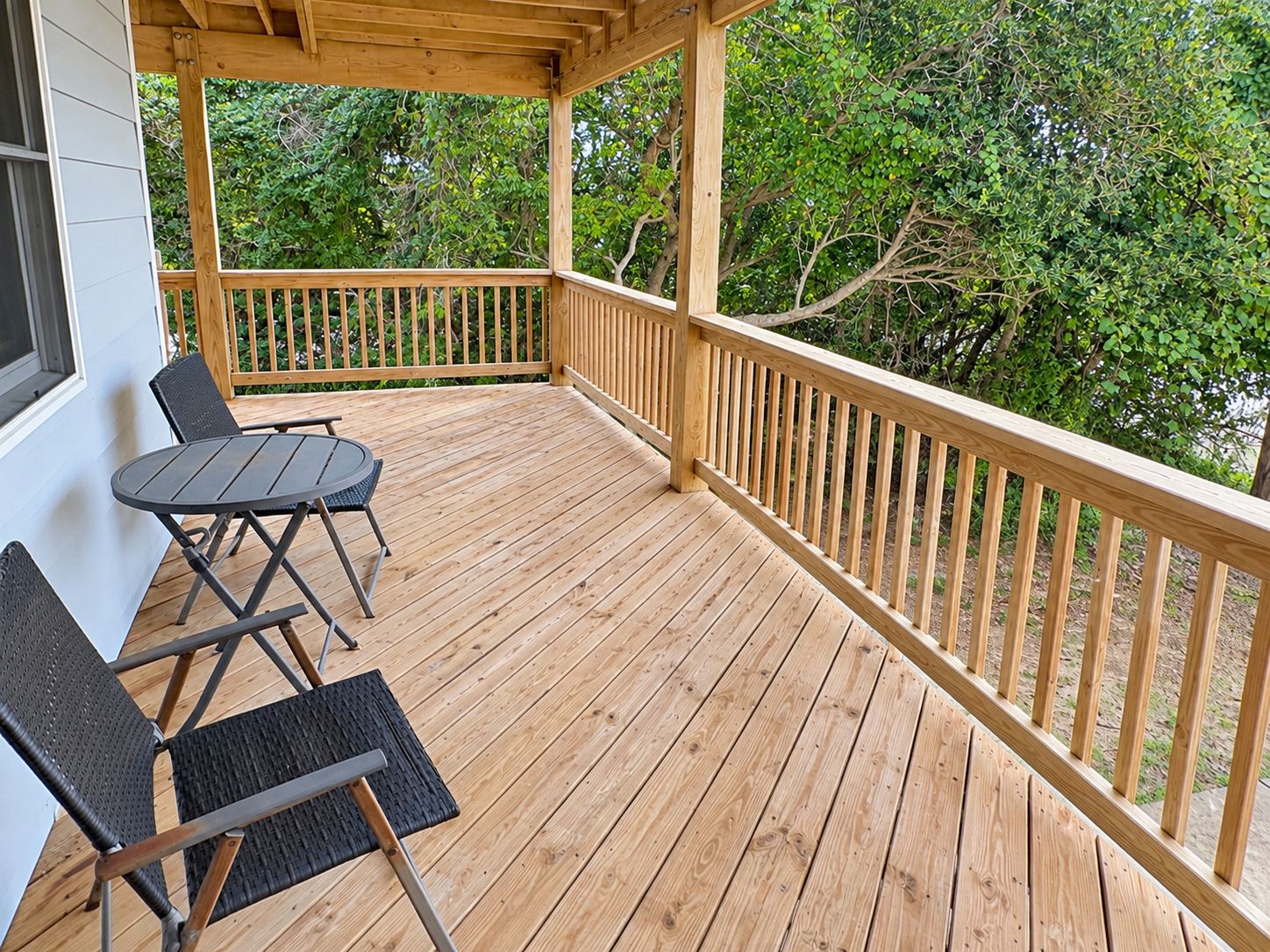 A wooden deck with a railing, a table, and two chairs.