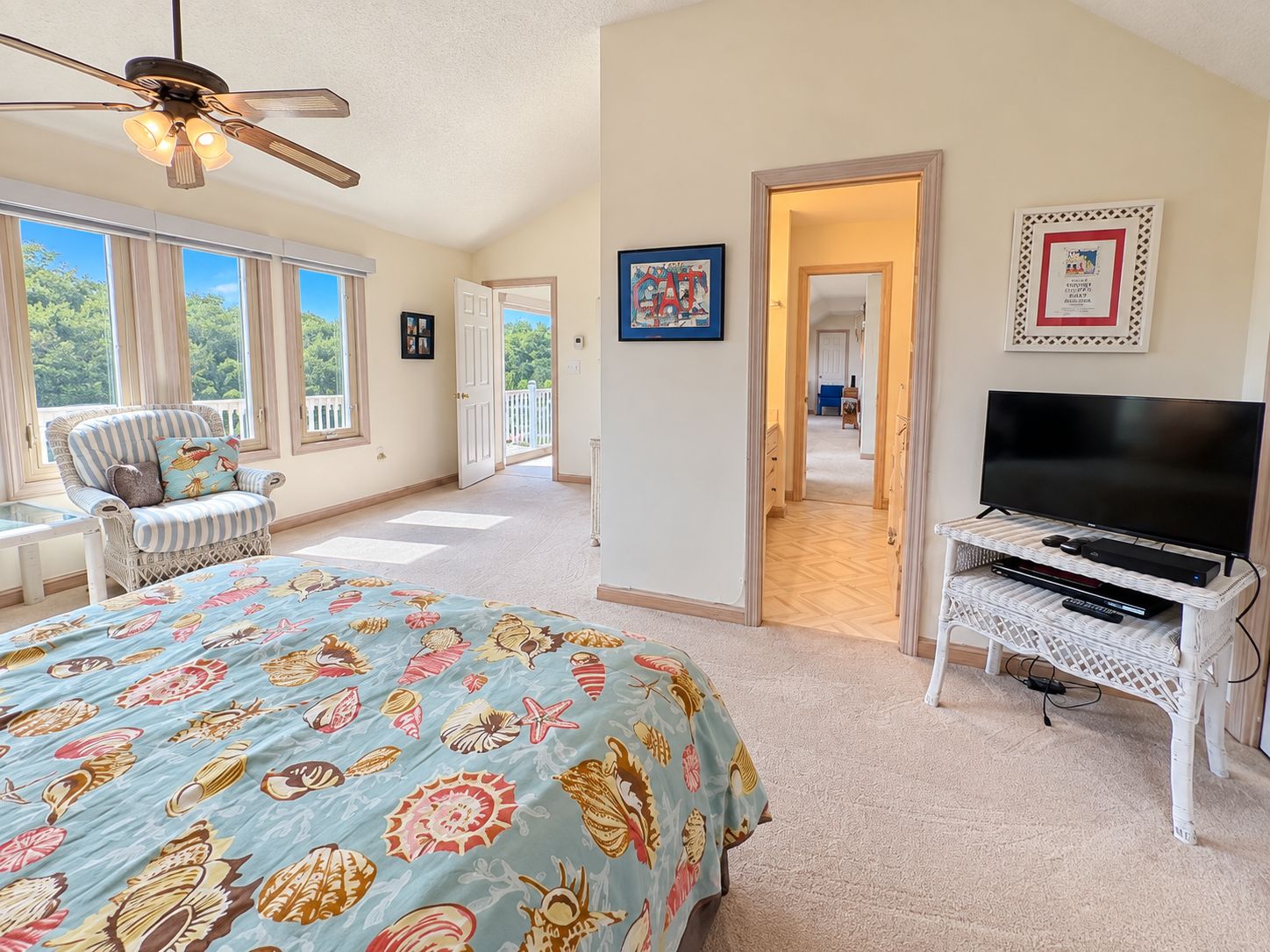 A bedroom with a bed, a television, a chair, and a ceiling fan.