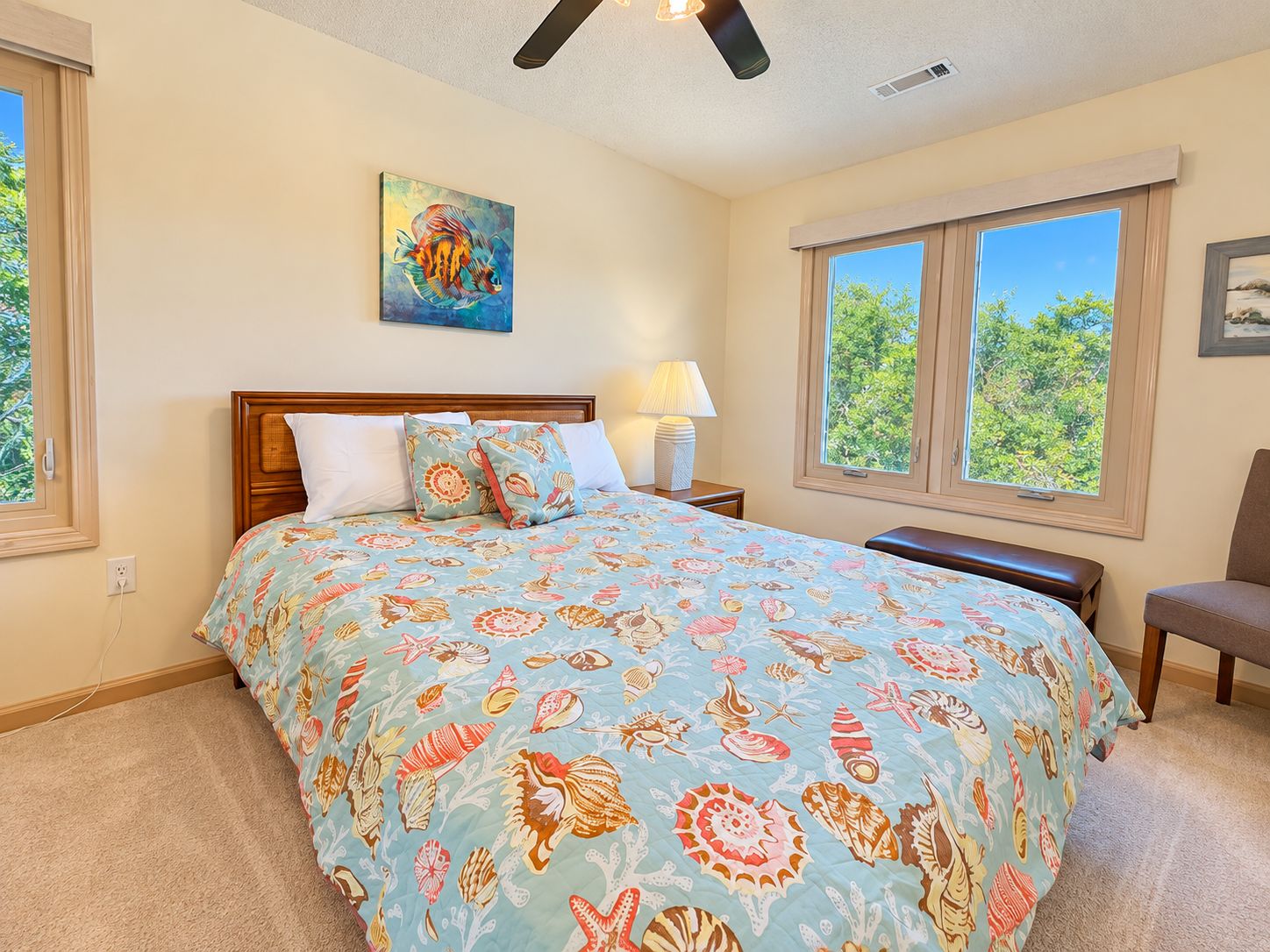 A bedroom with a bed, a nightstand, a chair, a window, and a painting on the wall.