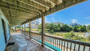 A wooden deck with a view of a swimming pool and houses in the background.