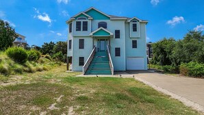 A two-story building with a front staircase, a garage, and a grassy front yard.