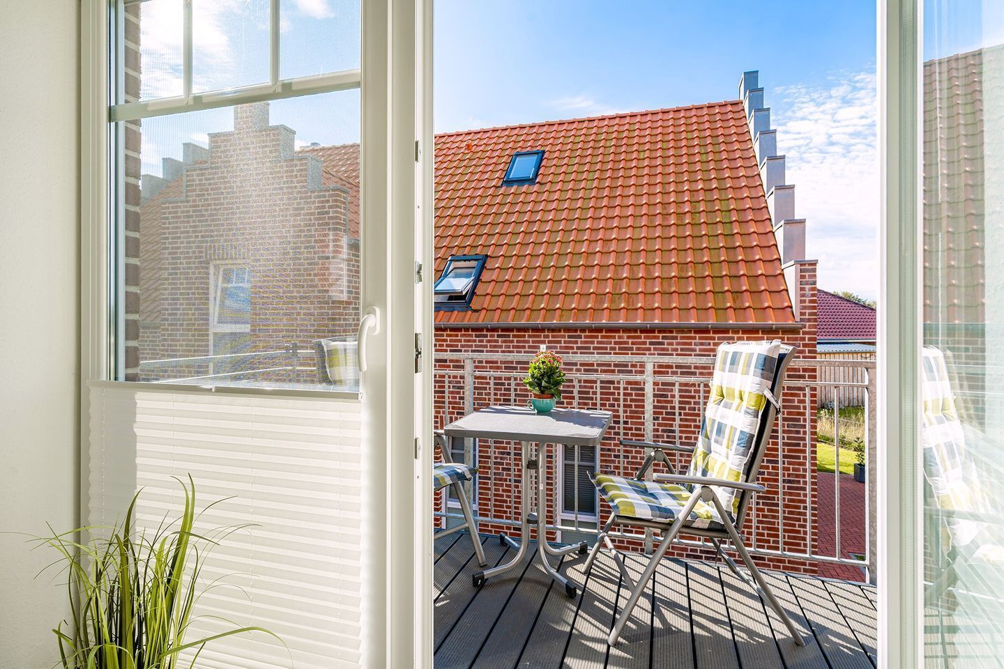 A balcony with a table, chairs, and a potted plant.