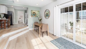 Un espacio habitable moderno con comedor, cocina y un amplio ventanal corredero que da a un balcón.
