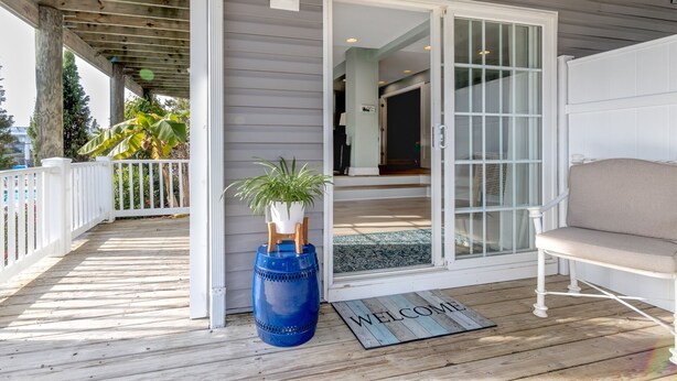 A wooden deck with a white railing, a blue barrel, and a welcome mat. - Sandbridge Beach Bay Getaway  (Virginia Beach)