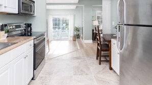 A modern kitchen with white cabinets, stainless steel appliances, and a large refrigerator. - Sandbridge Beach Bay Getaway  (Virginia Beach)