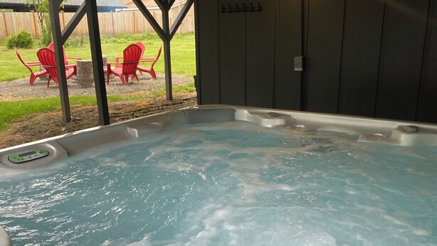 A hot tub with a control panel, surrounded by a wooden deck and red chairs. - Spacious Family Vacation Retreat! (Packwood)