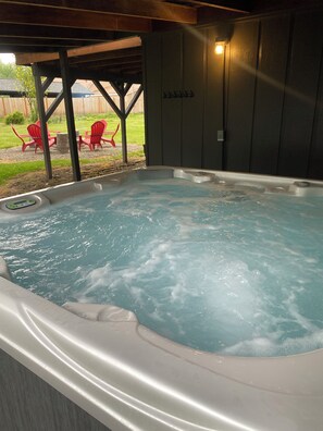 Ein Whirlpool mit Bedienfeld, umgeben von einer Holzdielen-Terrasse und roten Stühlen.