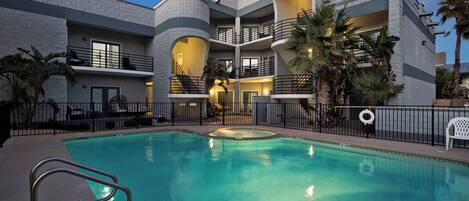 Un edificio moderno con piscina, varios balcones y zonas de estar al aire libre.
