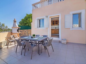 Un patio con tavolo imbandito per quattro persone, circondato da sedie e un muro in pietra con un camino.