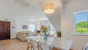 Una habitación de hotel moderna con comedor, chimenea y un amplio ventanal con vistas.