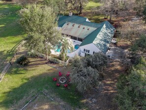 A large house with a green roof, surrounded by a well-maintained lawn and trees. - Family Friendly Farm House- 10 minutes from WEC (Ocala)