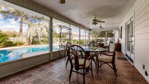 A covered patio with a pool view, wooden chairs, and ceiling fans. - Family Friendly Farm House- 10 minutes from WEC (Ocala)