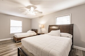 A bedroom with two beds, a ceiling fan, and a nightstand with a lamp. - Family Friendly Farm House- 10 minutes from WEC (Ocala)
