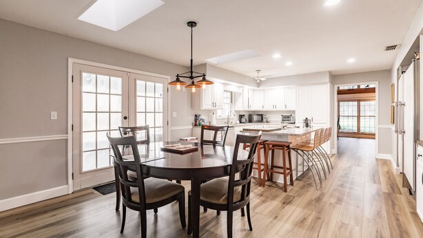 A spacious kitchen with white cabinets, a central island, and a dining area with a round table and chairs. - Family Friendly Farm House- 10 minutes from WEC (Ocala)
