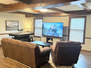 A living room with a television, two sofas, a coffee table, and a dining table.