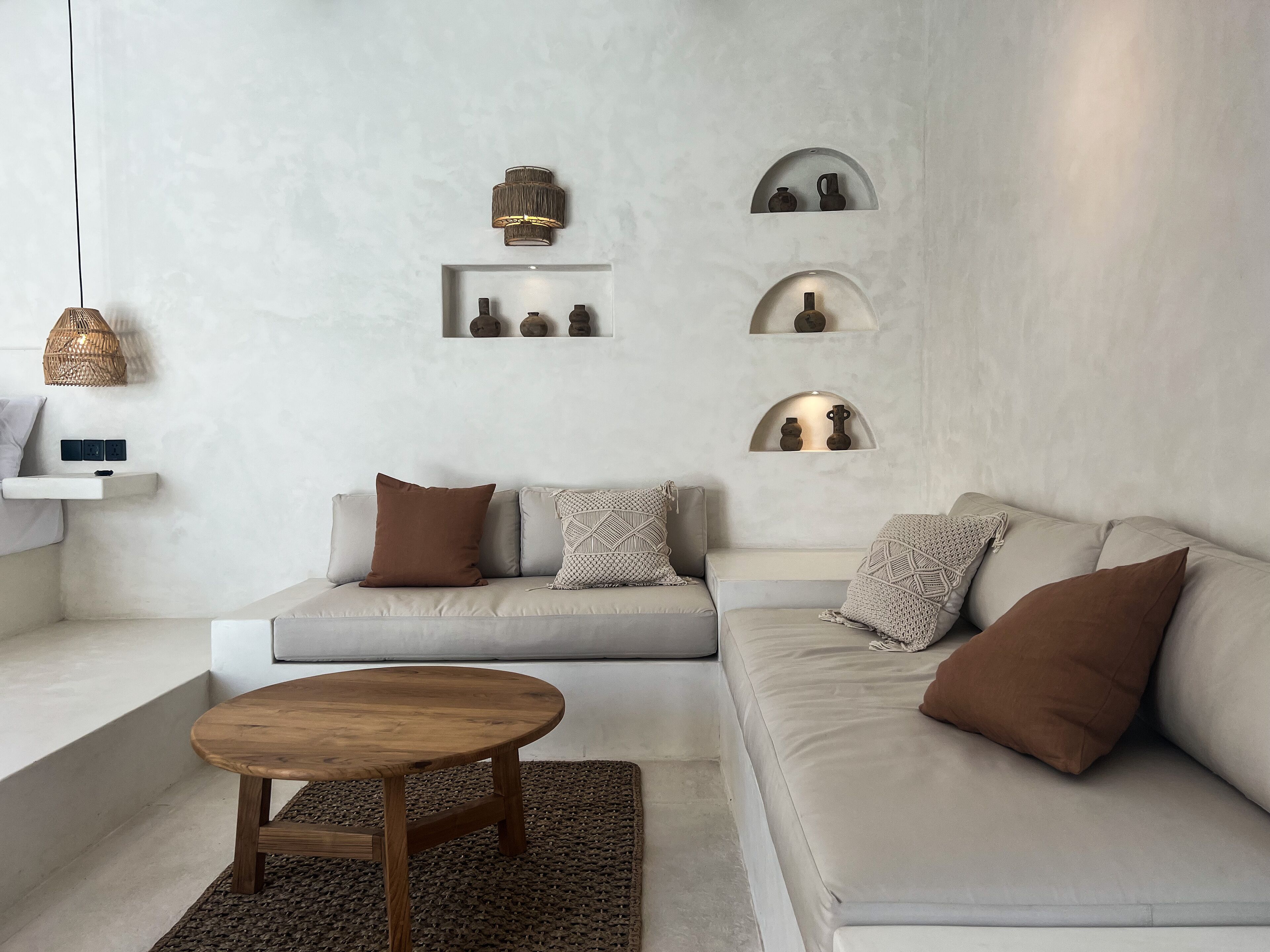 A modern living room with a light-colored sofa, a wooden coffee table, and decorative shelves with pottery.