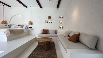 Uma sala de estar moderna com um sofá, uma mesa de centro e um tapete. Há prateleiras fixadas na parede com objetos decorativos.