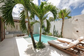 A poolside area with lounge chairs, a small pool, and tropical plants. - Breathe Boutique (Pecatu)