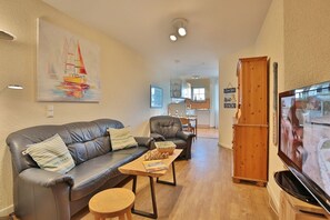 Un salon chaleureux avec un canapé en cuir, une table basse en bois et un téléviseur.