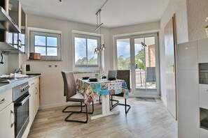 A modern kitchen with a dining table, chairs, and a view of the outdoors.