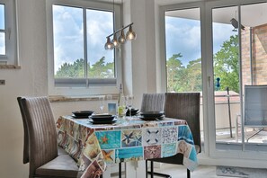 A dining area with a table set for four, large windows, and a view of trees.