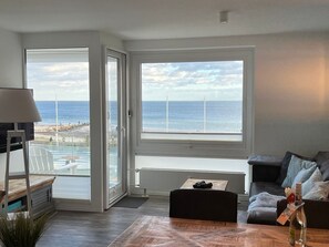 A living room with a view of the ocean, a sofa, a coffee table, and a lamp.