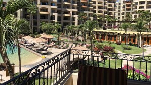 A hotel with multiple balconies, a pool area, and lush landscaping. - Medano Beachfront Resort-Luxury Villa Overlooking Pool and Sea of Cortez! (Cabo San Lucas)