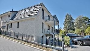 Un edificio moderno de dos pisos con balcón y zona de estacionamiento.