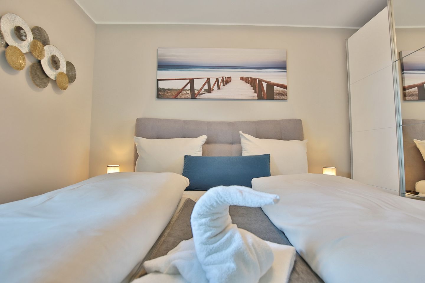 Habitación de hotel con dos camas, un cuadro de una playa y una toalla en el suelo.