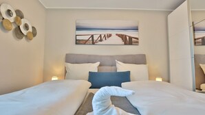 Habitación de hotel con dos camas, un cuadro de una playa y una toalla en el suelo.