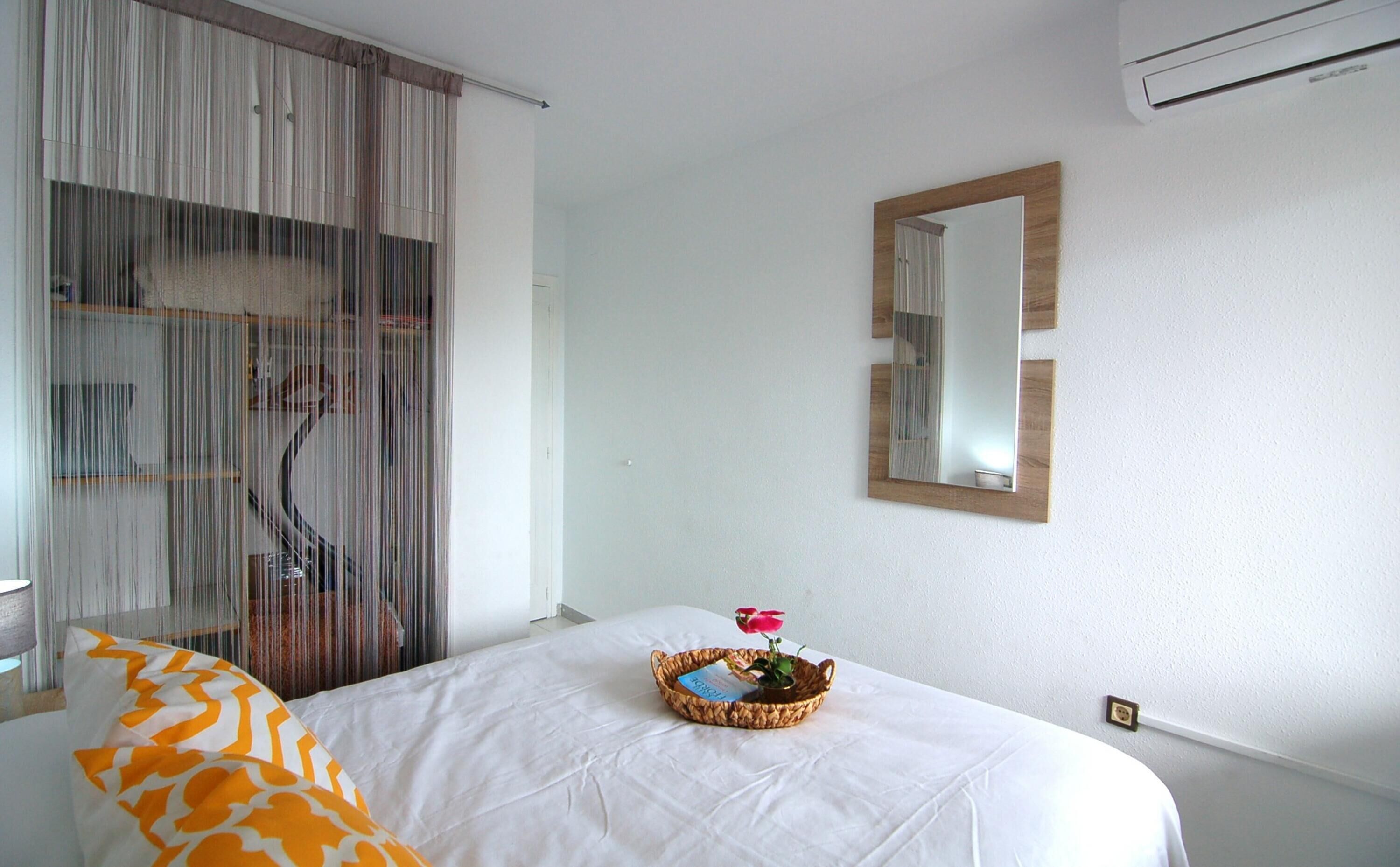 Une chambre d’hôtel avec un lit, une table de chevet, un miroir et une fenêtre avec des rideaux.