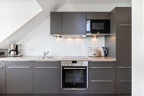 Eine moderne Küche mit grauen Schränken, einem eingebauten Backofen, einer Mikrowelle und einer Kaffeemaschine.