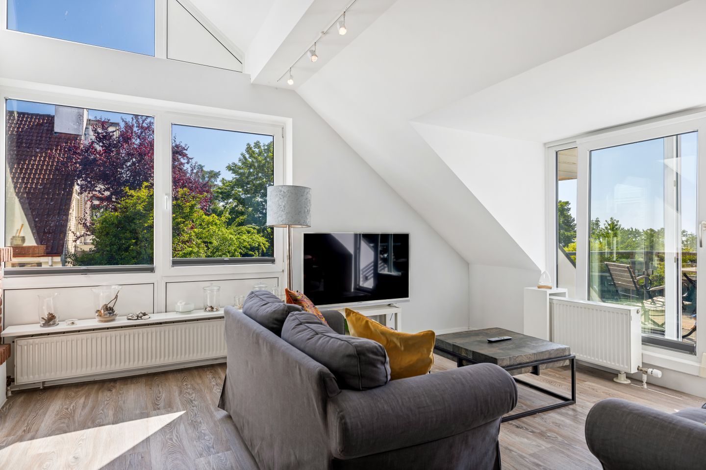 Ein modernes Wohnzimmer mit großem Fenster, Flachbildfernseher und einer Couch.