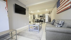 Un salon moderne avec un canapé gris, une table basse et un téléviseur.