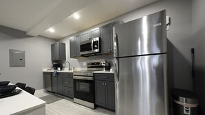 Une cuisine moderne dotée d’appareils électroménagers en acier inoxydable, de meubles de couleur grise et d’un plan de travail blanc.