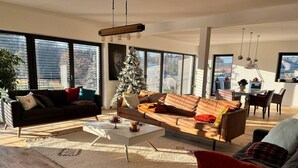 A modern living room with a large window, a Christmas tree, and a dining area. - House - Sleeps 8 - Pets Ok - Garden - Parking (Berdorf)